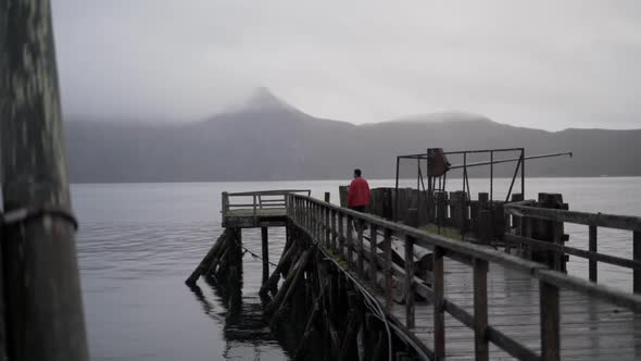 Hiker Standing On Old Wooden Pier In Fjord