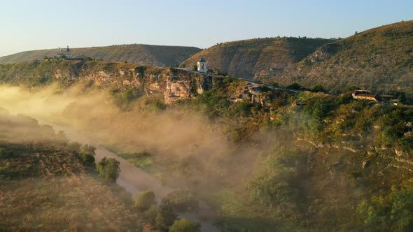 Aerial drone view of the Old Orhei at sunset. Valley with river and fog, monastery located on a hill