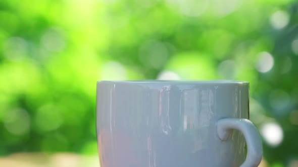 Hot Drink in a Cup Against the Background of a Summer Garden in the Morning