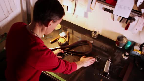 Tailor Making a Belt and Wipes the Leather Scraps Off the Table