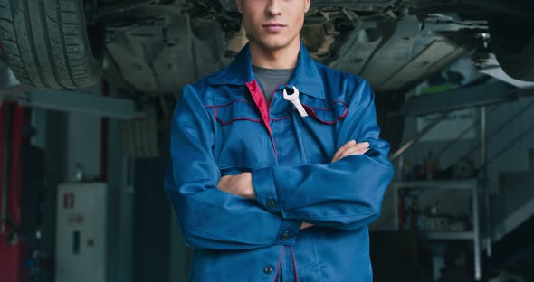 Young Confident Mechanic, Looking Seriously at Camera with Folded Arms, Garage Background