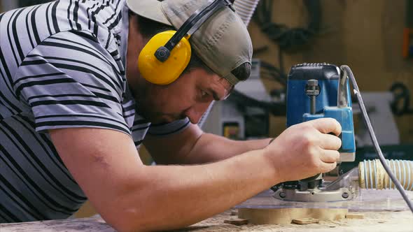 Male Carpenter Working with Milling Machine for Cutting Figure Wooden Detail