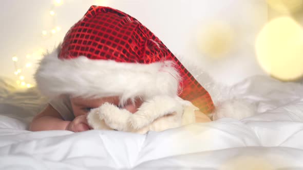 Adorable Baby Girl in Santa Hat Lying on White Bed