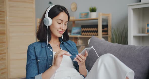 Slow Motion of Pretty Girl Listening To Music in Headphones Using Smartphone