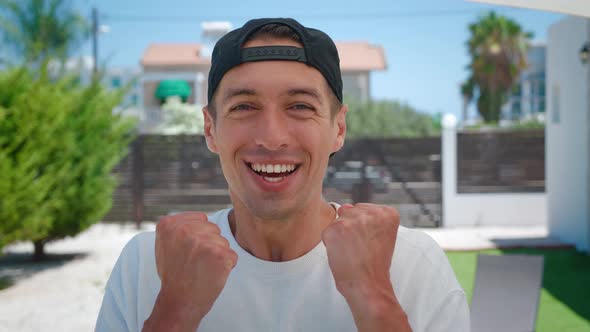 Overjoyed Young Man Looking at Camera and Makes Makes Triumph Gesture