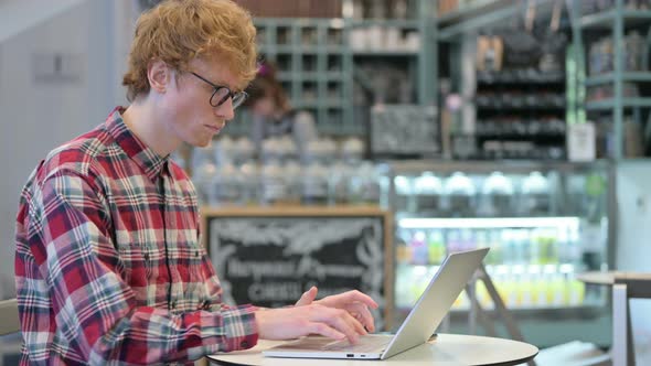 Professional Young Redhead Man in Cafe Using Laptop 