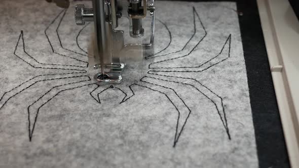 Embroidery machine creating textile design. Spider embroidery for Halloween