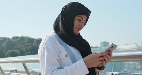 Muslim Woman Using Smartphone in Modern City Street