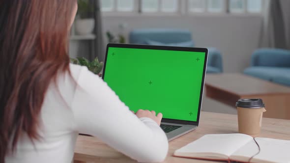 Girl Typing On Computer Keyboard Of A Laptop Computer With Green Screen Display At Home