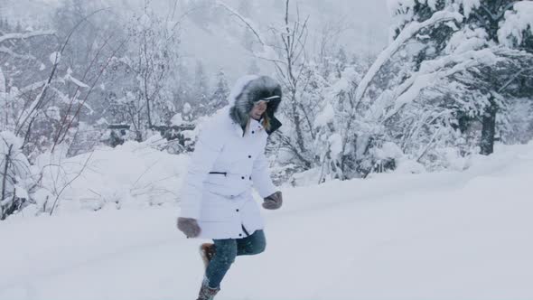 Happy Smiling Young Woman Jumping Into High White Snowdrift on Winter Cold Day