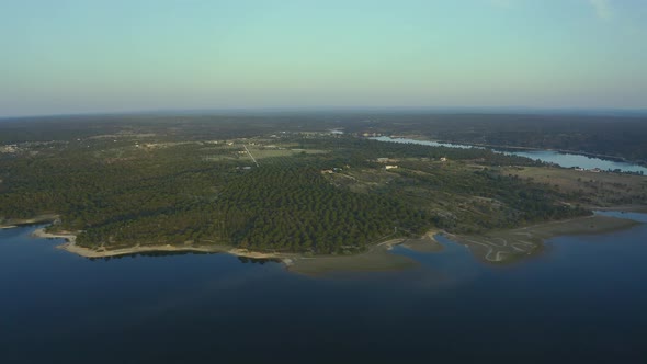 Aerial view of green rural landscape with huge dam at sunrise time, Alentejo, Europe