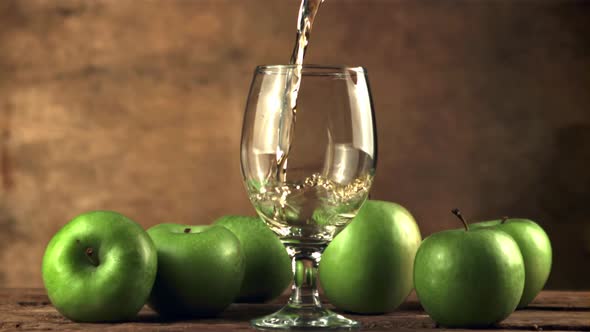 Super Slow Motion in the Glass on the Table Pours a Jet of Apple Juice