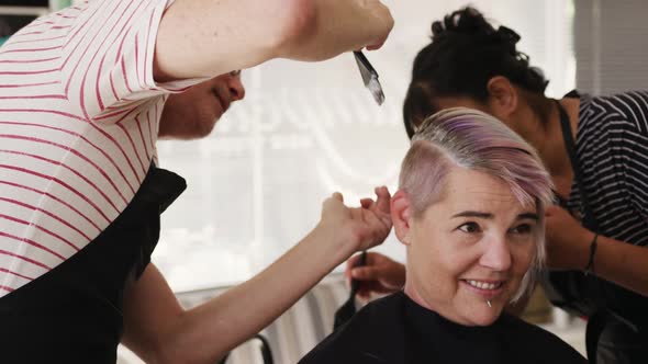 Side view woman having her hair styled by two hairdressers