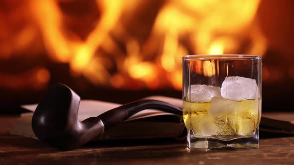 A Glass of Whisky, an Open Book, And a Pipe on The Table