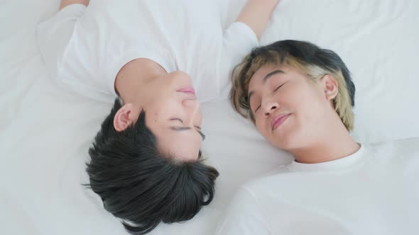 Asian young male gay family lying down on bed after wake up in morning at home.