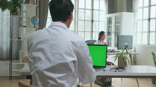 Asian Man Doctor Having Video Conference On Laptop Computer With Mock Up Green Screen Display