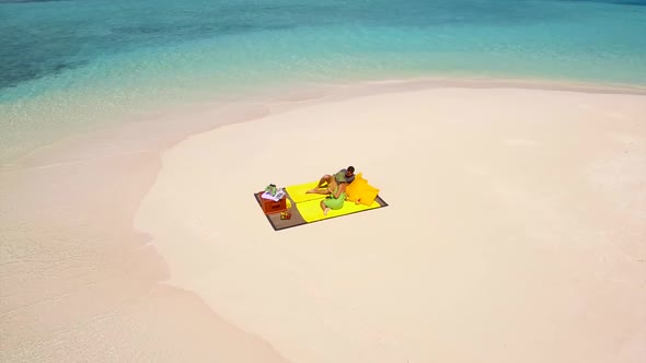 Aerial drone view of a man and woman couple having a picnic meal on a tropical island beach