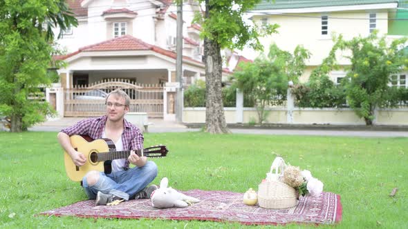 Portrait of Man Having Picnic While Playing the Guitar Outdoors