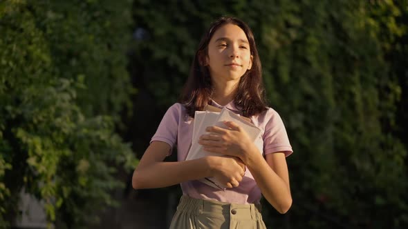 Medium Shot Portrait of Happy Intelligent Caucasian Teenage Girl Standing at Golden Sunset with