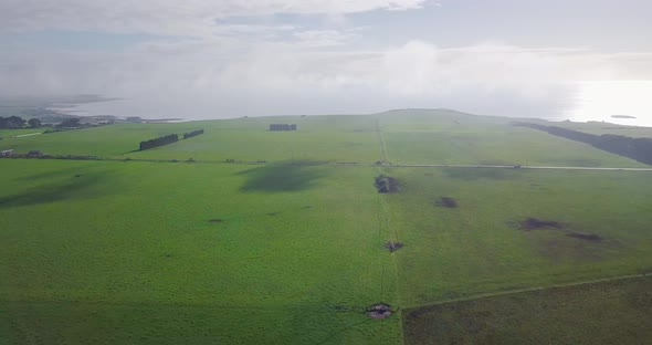 Amazing aerial flight over green field towards coastline in Tasmania, Australia