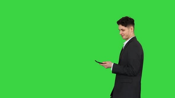 Happy Successful Businessman Dancing Listening Music From the Phone And Walking on a Green Screen