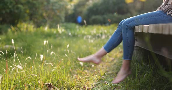 Woman sitting on the wooden walking path and swing the legs