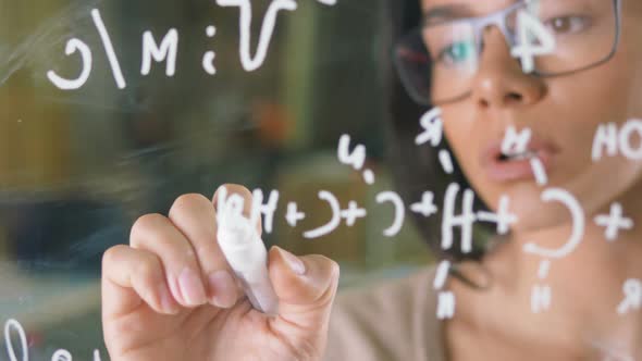 Young Attractive Female Office Worker Writing on Glass Whiteboard Close Up