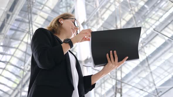 Portrait Of Business Woman With Papers Wearing Wireless Earphones And Smartwatch