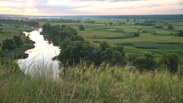 Panoramic View of River Between Fields During Sundown.