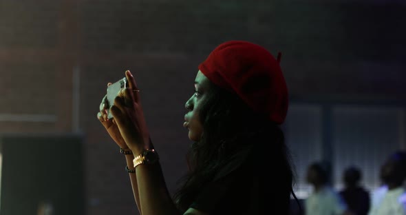 AfricanAmerican Woman in a Red Beret Shoots Video on Her Phone During a Concert