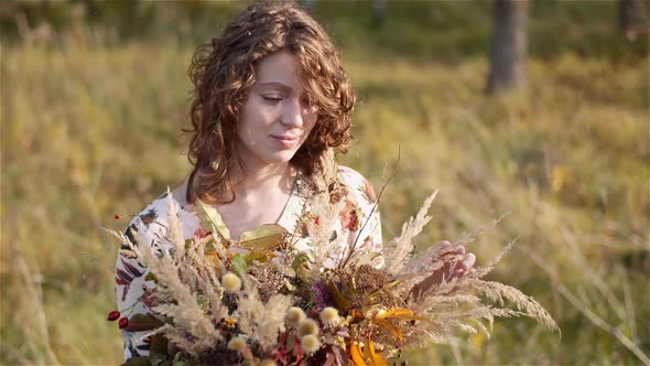 Portrait of Woman Looking at Bouquet of Wild Flowers in Summer.