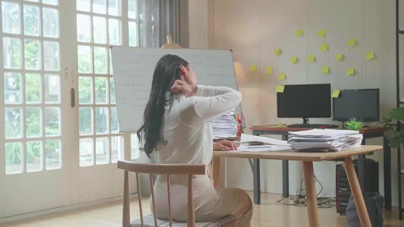 Back View Of Asian Woman Stretching After Working Hard With Documents At The Office
