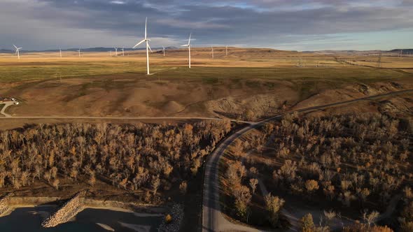 Cinematic aerial footage of wind turbines in Canada during a sunrise that illuminates the Rocky moun