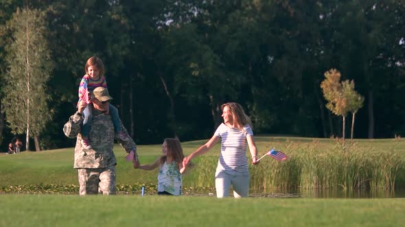 Soldier in Camoubackgrounde with His Family in the Park.