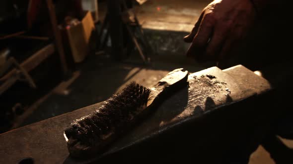 Mid-section of blacksmith holding wire brush