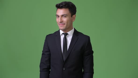 Young Handsome Hispanic Businessman Against Green Background