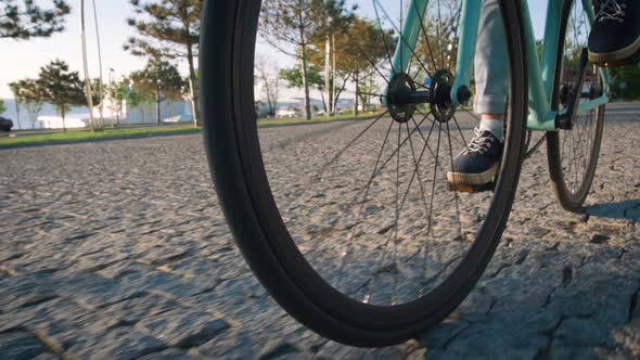 Young Stylish Woman Cyclist Enjoying Fixed Gear Bike Riding Outdoors at Sunrise Near the Sea Close