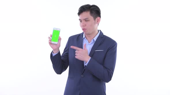 Happy Young Asian Businessman Showing Phone and Giving Thumbs Up