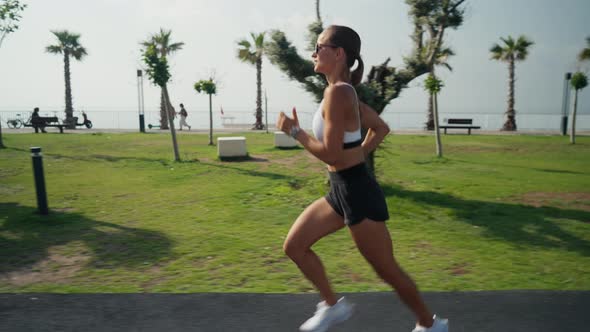 Outdoor Shot of Fitness Young Woman Jogging Along the Beach