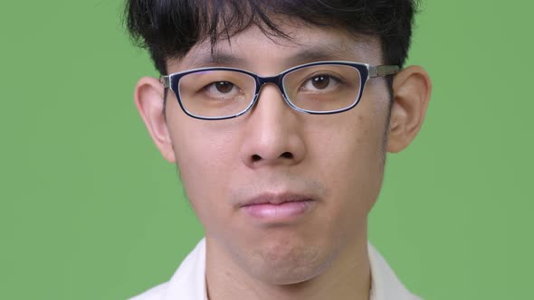 Head Shot of Young Asian Businessman Against Green Background