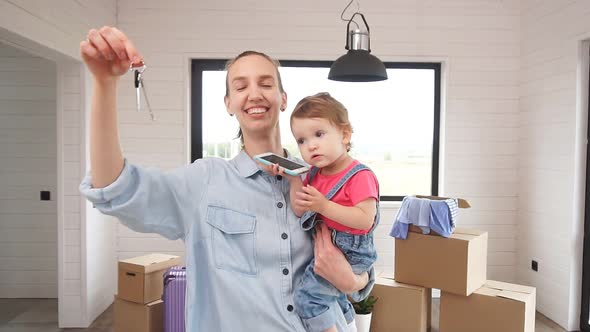 Young Family Moves To a New House. Mother with a Little Daughter in Her Arms Posing and Holding a