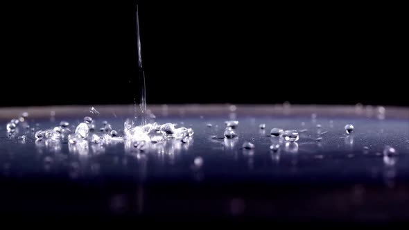 Water droplets bouncing on shinny surface.