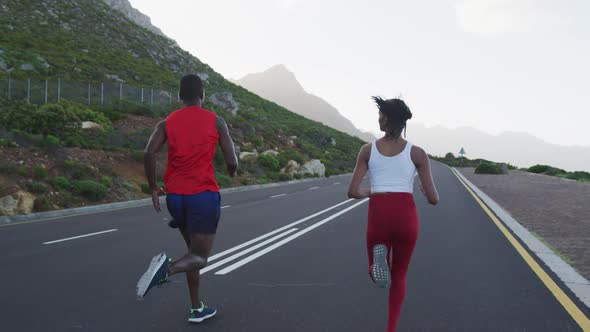 Diverse fit couple exercising running on a country road near mountains