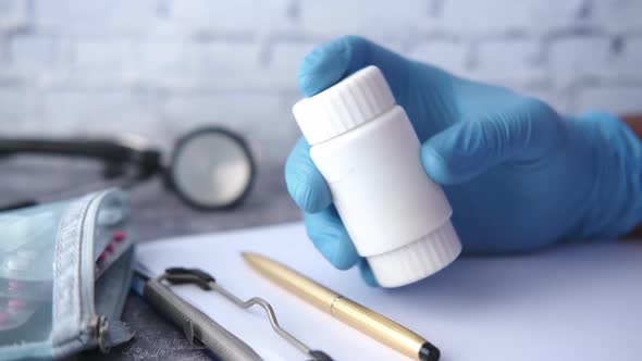 Doctor Hand in Protective Gloves Holding Pill Container