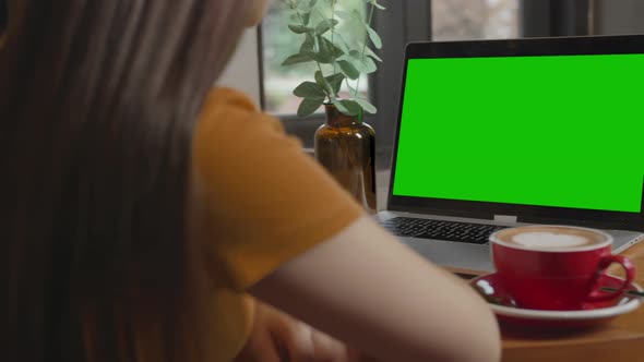 Girl Using Computer With Green Screen In Coffee Shop