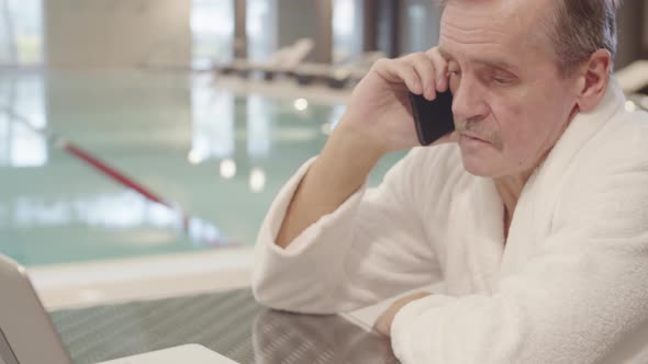 Businessman Having Phone Call in Swimming Pool