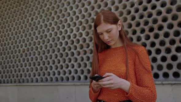 Red Haired Girl Standing on Street and Texting on Cell Phone