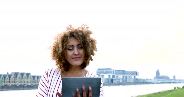 Smiling woman using digital tablet at Rhine riverside in Cologne