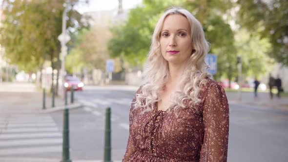 A Middleaged Caucasian Woman Looks Seriously at the Camera in an Urban Area