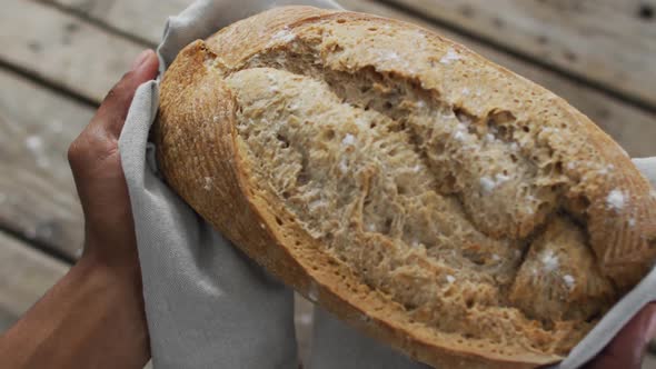 Video of bread in hands on wooden worktop seeing from above